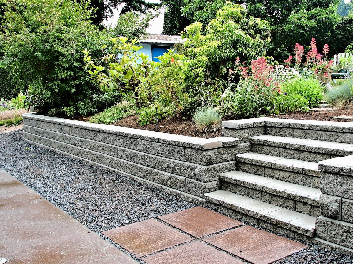 A stone retaining wall with built-in steps shaping a residential garden