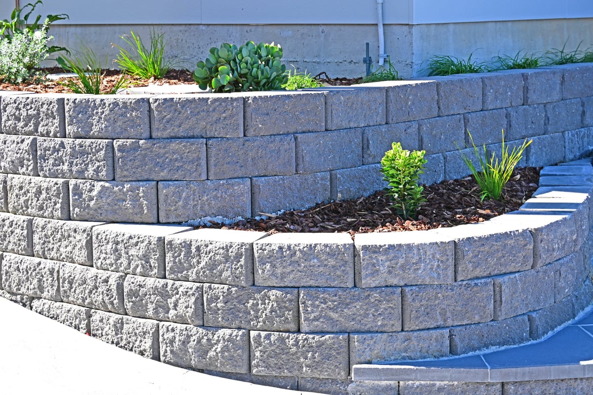 Curved concrete block retaining wall built into a landscaped garden
