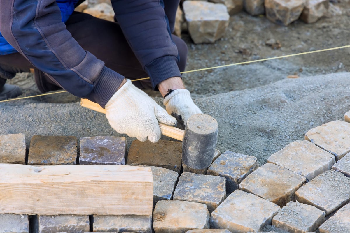Masonry worker installing stone pavers for a high-end patio and walkway