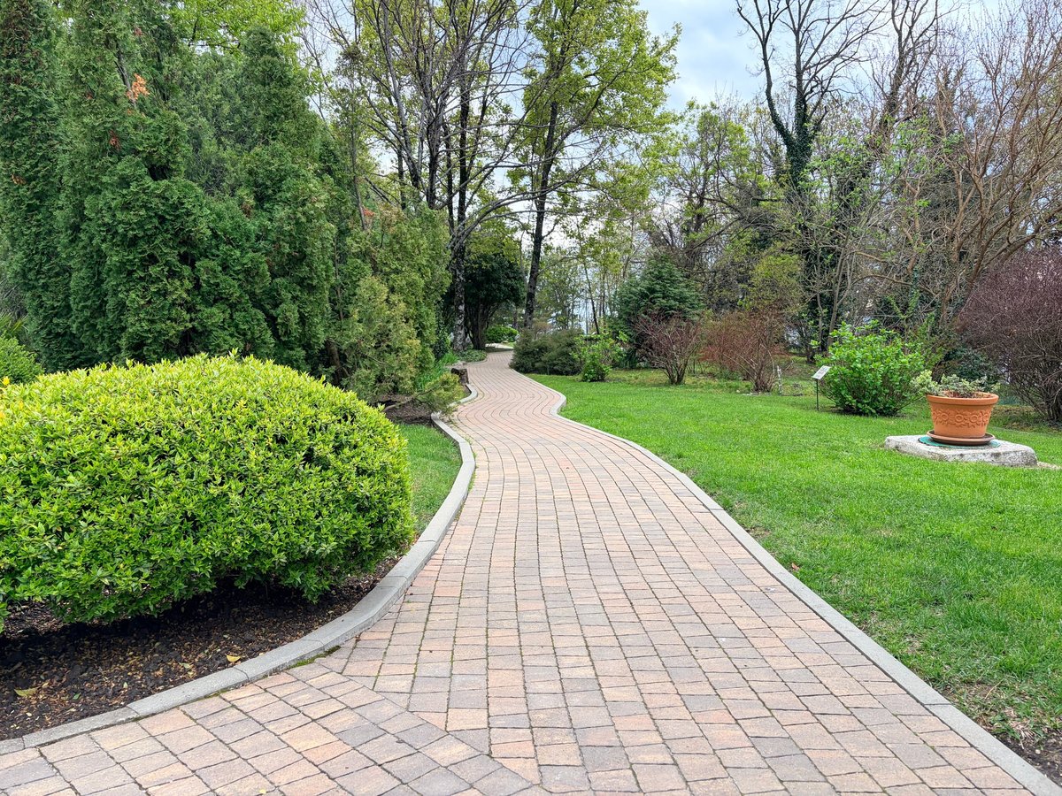Interlocking paver walkway bordered by concrete curbs and green lawns