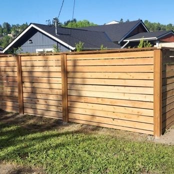 Horizontal wooden fence panels in backyard with residential houses visible in background